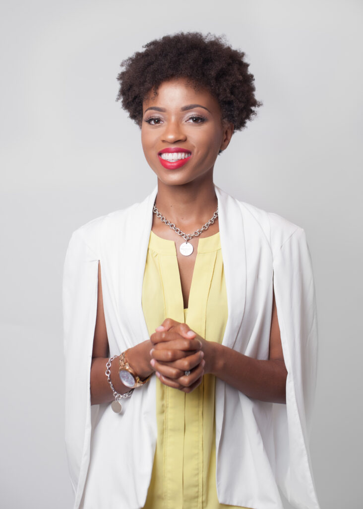 Emerald Sparks in a yellow dress and white coat smiling